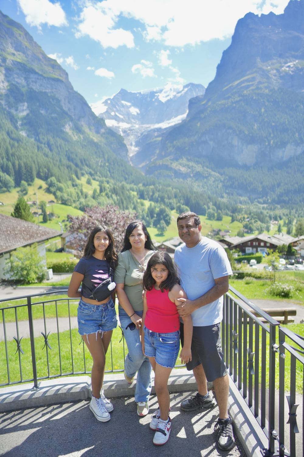 A family at a railing above the Grindelwald valley, the glaciers and peaks behind them