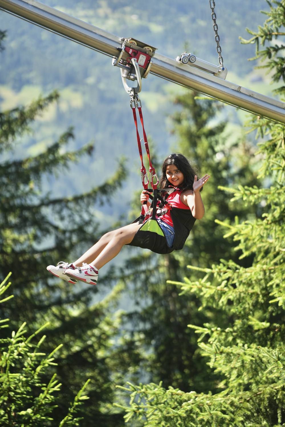 A young guest flying down the zipline through the trees at Grindelwald First