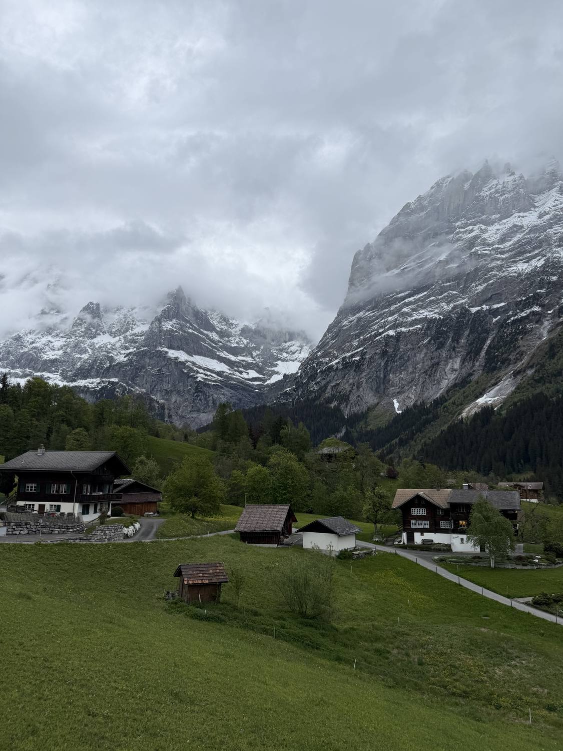 Wooden chalets on the meadows of Grindelwald with cloud drifting across the Wetterhorn