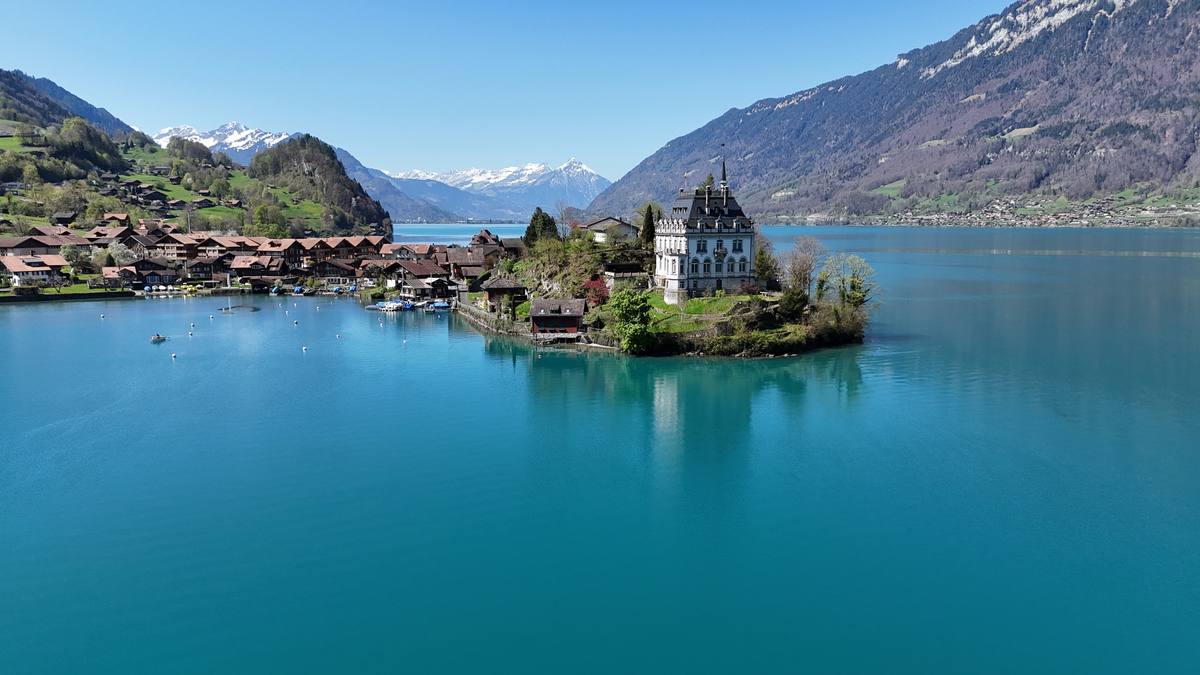 Schloss Seeburg on its peninsula in Iseltwald, surrounded by the turquoise water of Lake Brienz