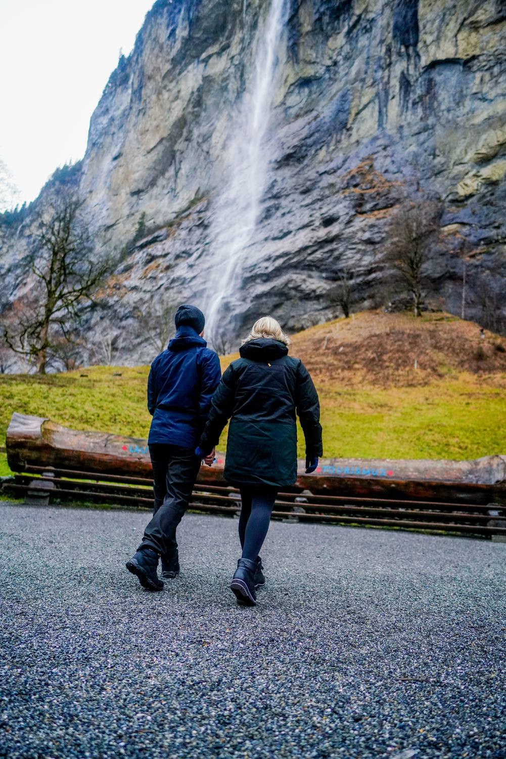 A couple walking hand in hand towards the Staubbach Falls in Lauterbrunnen