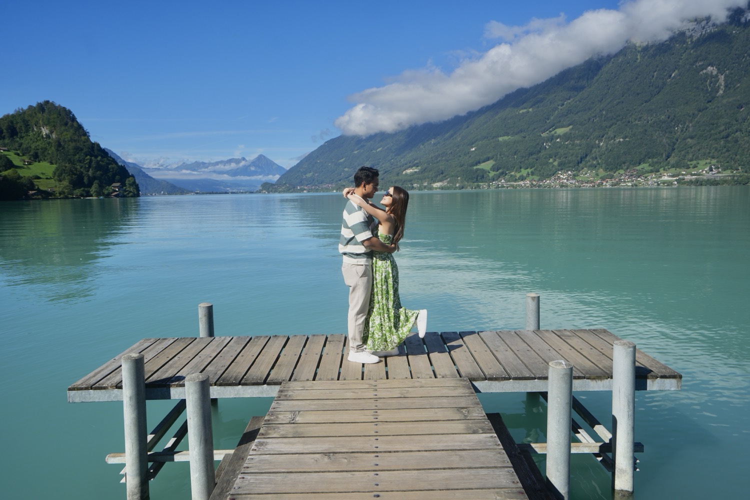 A couple on the wooden pier in Iseltwald, with Lake Brienz and the mountains behind them