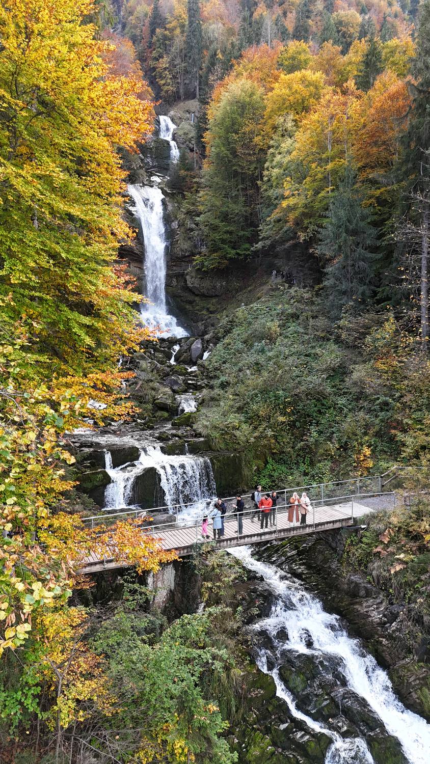The Giessbach Falls in autumn, with guests on the bridge between two cascades