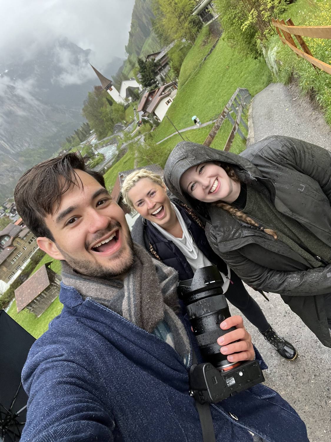 Three guests laughing in the rain in Lauterbrunnen, the guide holding his camera