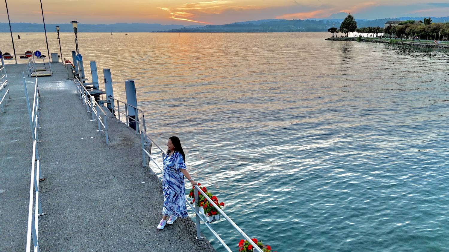 A guest walking out along the pier at Rapperswil as the sun sets over Lake Zurich