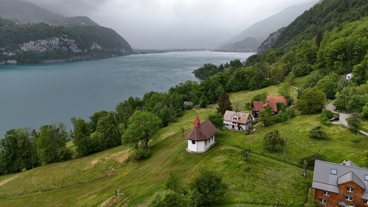 A small chapel on a meadow above the Walensee, with cloud hanging over the lake