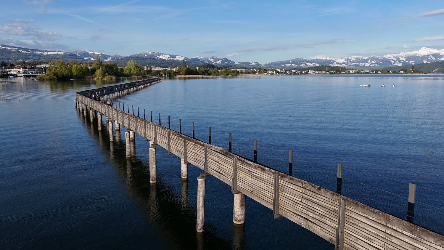 The wooden pilgrims' bridge from Rapperswil across to Hurden, snow-covered Alps behind