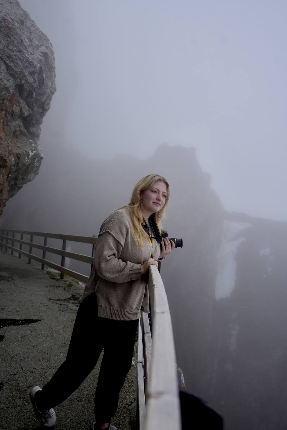 A guest with her camera at the summit railing on Pilatus, the rock lost in fog