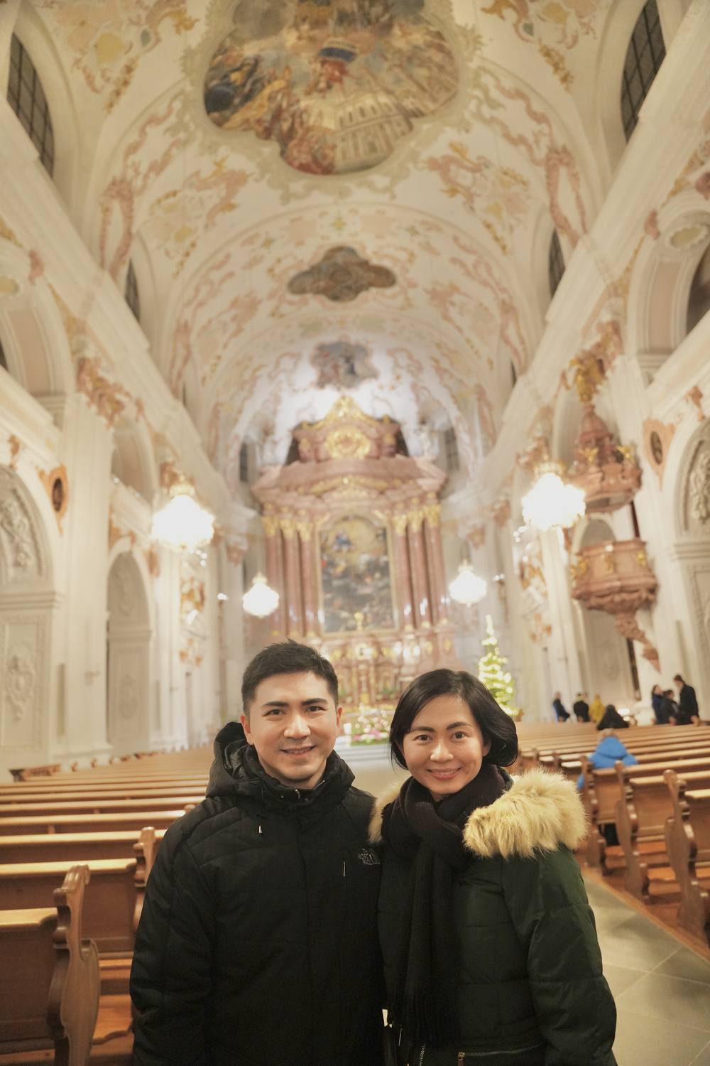 A couple in the Jesuit Church in Lucerne at Christmas, the gilded altar behind them