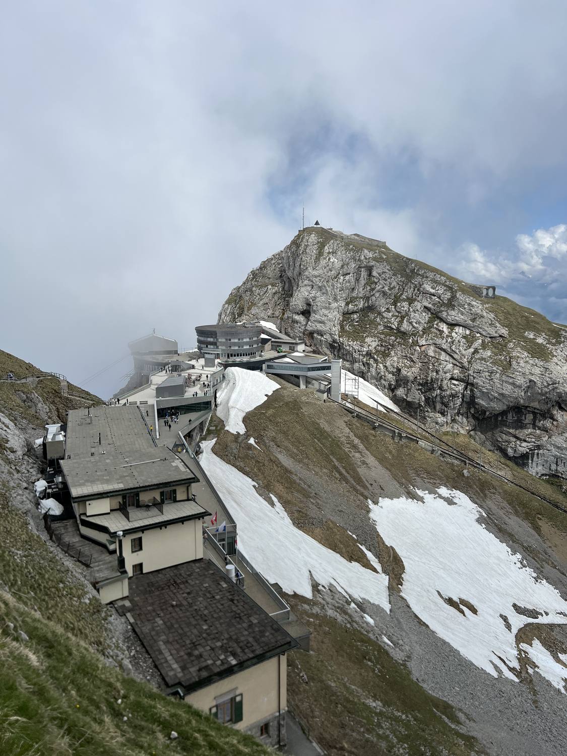The summit buildings of Pilatus Kulm on their ridge with cloud rolling past