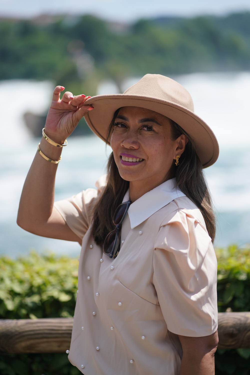 A guest in a wide-brimmed hat at the Rhine Falls, the water rushing behind her