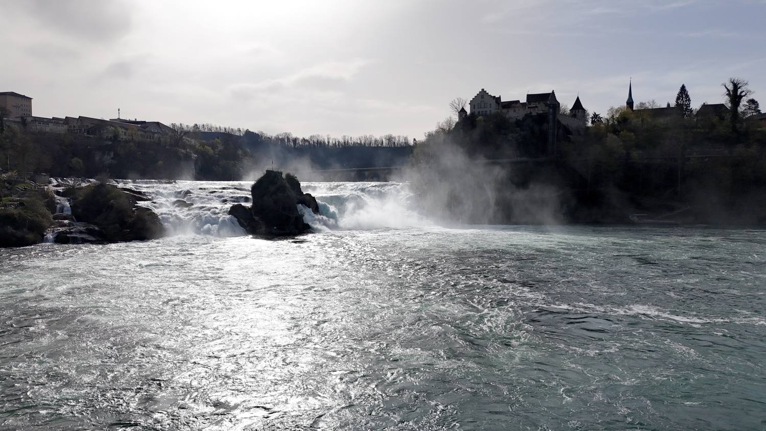 The Rhine Falls with the central rock in the spray and Schloss Laufen on the bank above