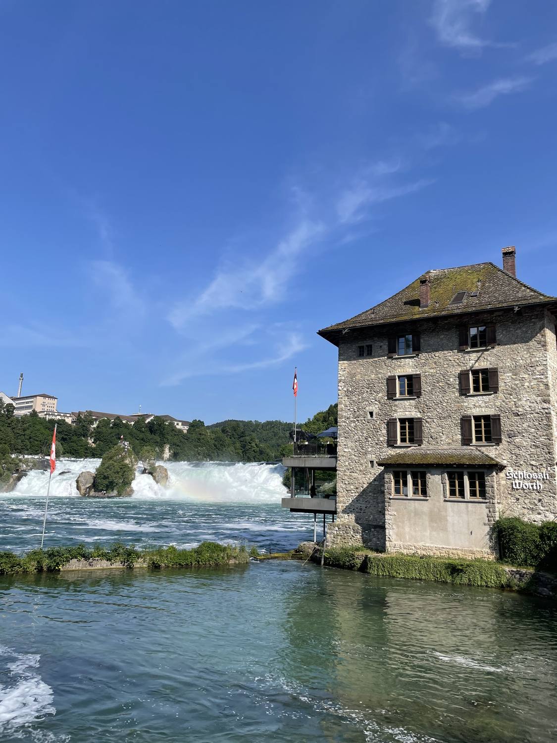 The Schloessli Woerth standing in the green water right beside the Rhine Falls
