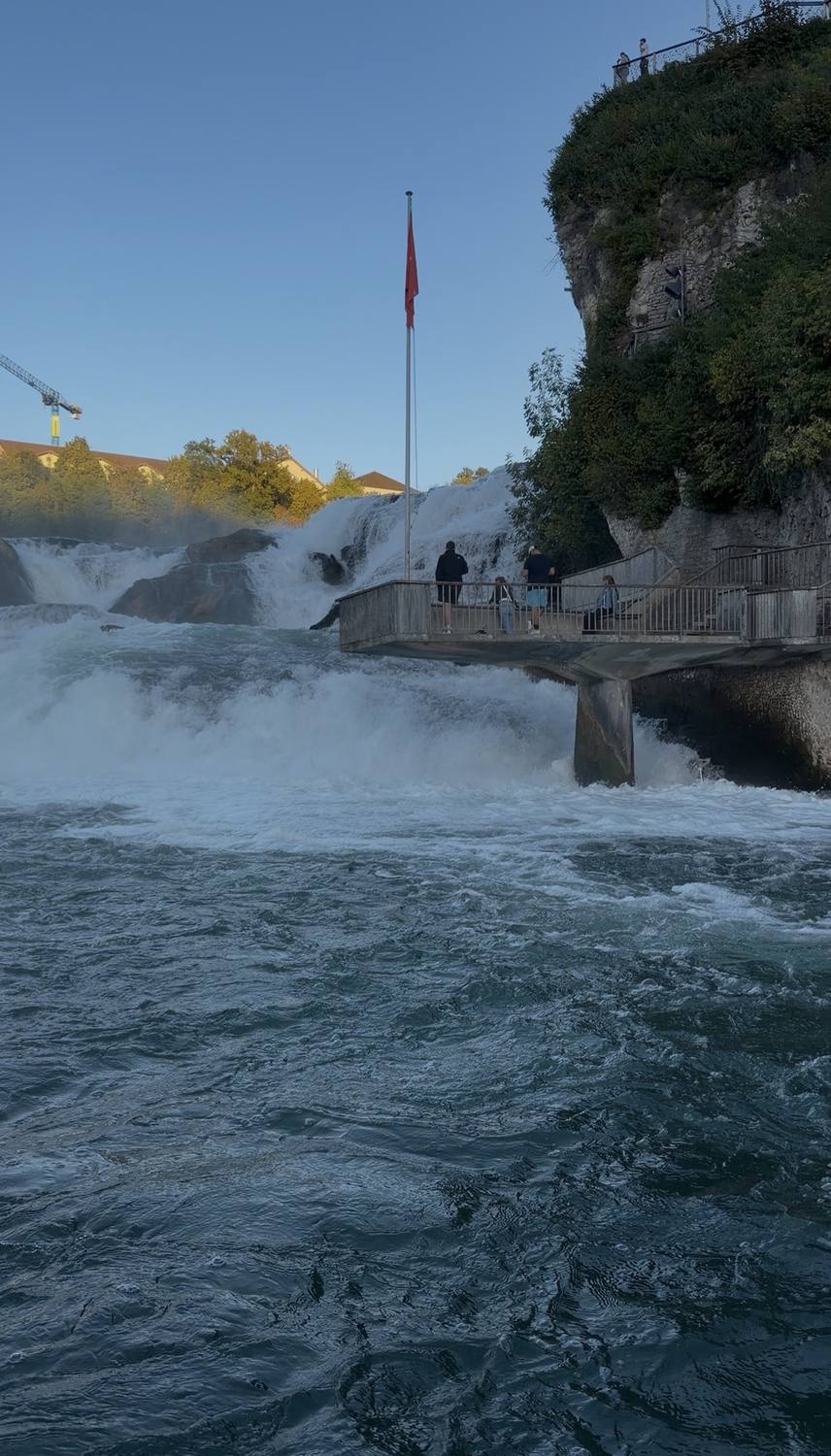 The Rhine Falls seen from water level, the flag on the rock above the white water
