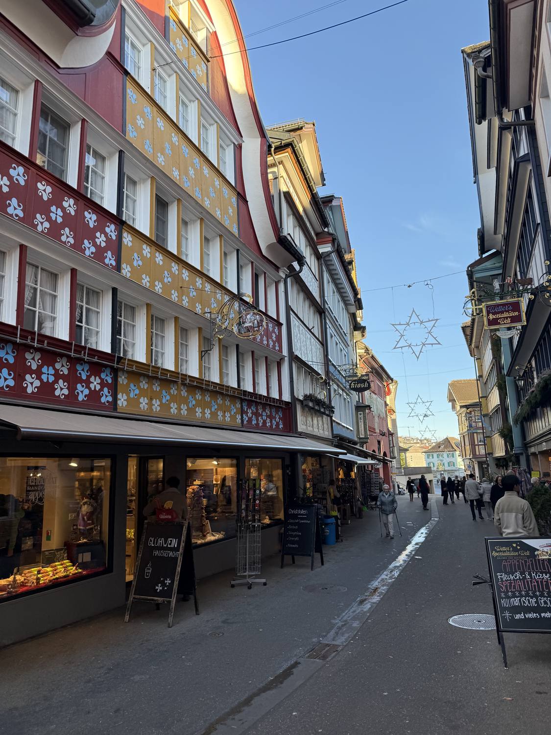 Shop windows glowing along the painted main street of Appenzell at dusk