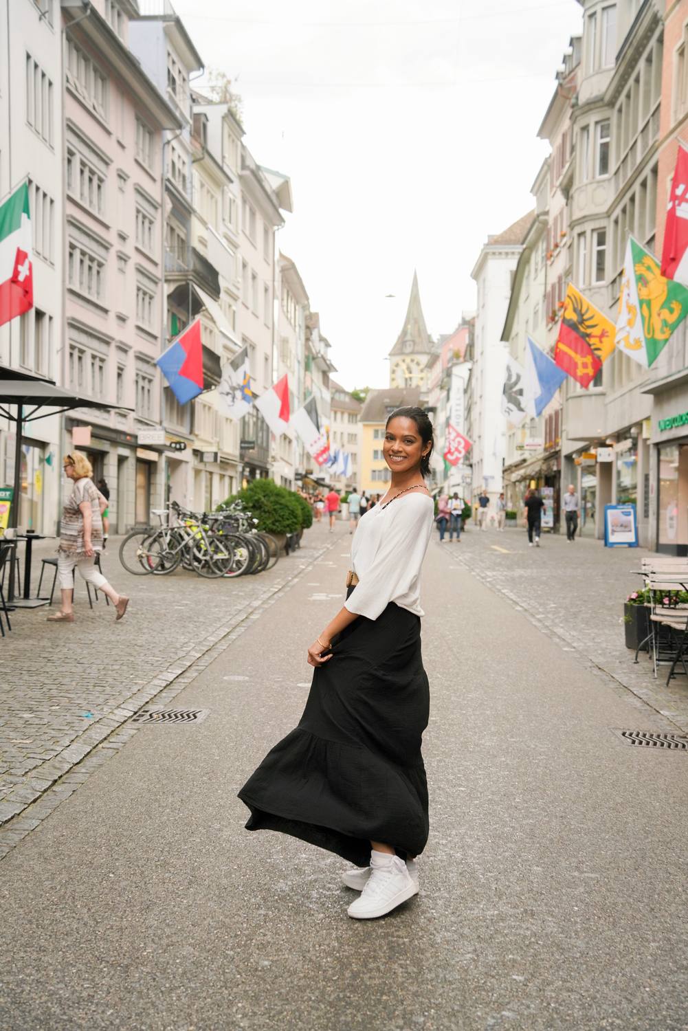 A guest in a Zurich old town lane hung with cantonal flags, a church spire at the end