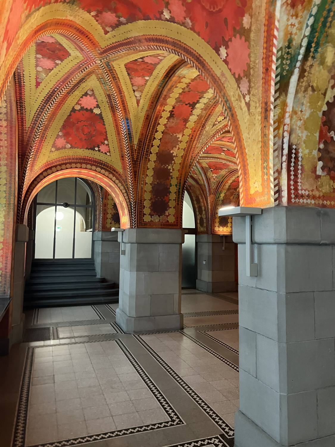 A richly painted vaulted passage in Zurich, its arches patterned in red and gold
