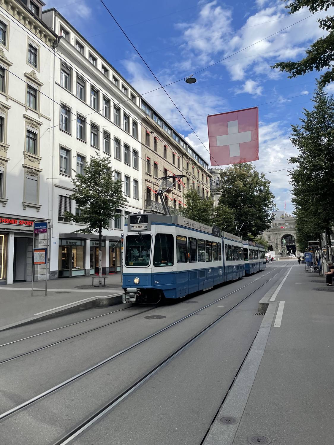A tram on Zurich's Bahnhofstrasse under a Swiss flag